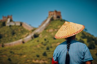 woman wearing hat facing The Great Wall of China