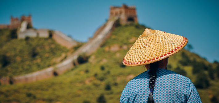 woman wearing hat facing The Great Wall of China