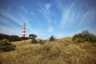 lighthouse on top of a mountain under a calm blue sky