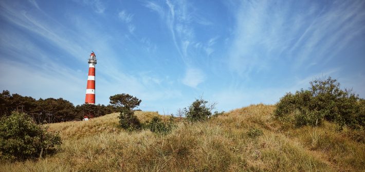 lighthouse on top of a mountain under a calm blue sky